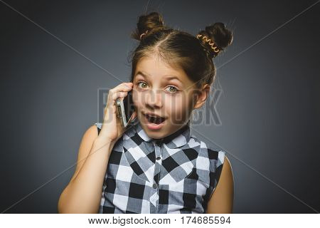 Closeup Portrait of happy girl with mobile or cell phone on gray background.