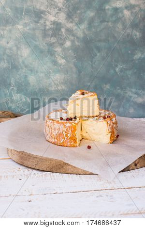 French German soft cheese with orange washed-rind fork red pepper corns cutting board rustic style