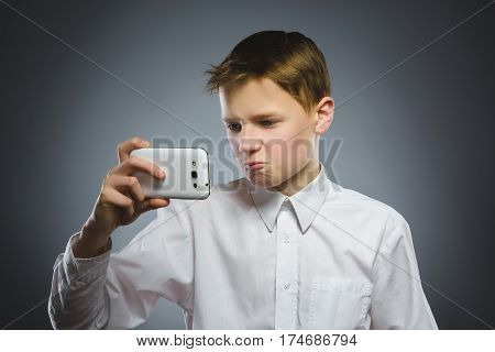 Portrait of offense boy with mobile or cell phone. Negative human emotion.