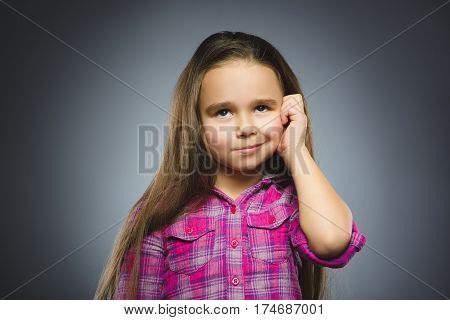 Closeup Thoughtful or contemptuous Young girl Looking Up with hand on glasses isolated on Gray Background.
