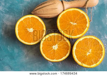 Bunch of ripe colorful oranges sliced in half with wood reamer on blue background template top view close up