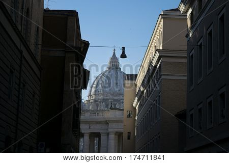 Saint Peter's dome in Rome seen through a typical roman alley