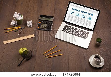 Laptop computer on wooden desk with office suplies
