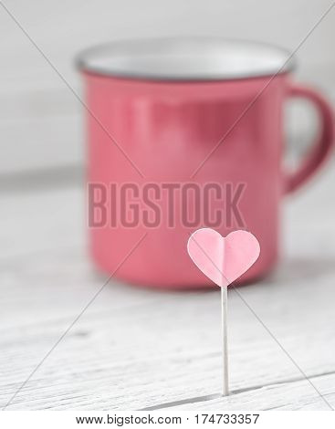 beautiful pink Cup with heart on a stick on a light wooden background, concept drinks