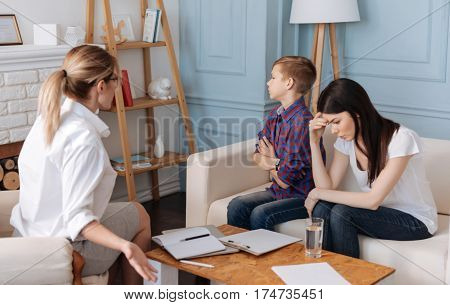 Generation gap. Young woman wearing white T-shirt feeling tired while visiting psychotherapy