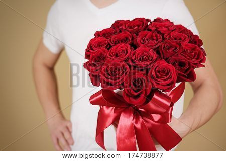 Man In White T Shirt Holding In Hand Rich Gift Bouquet Of 21 Red Roses. Composition Of Flowers In A