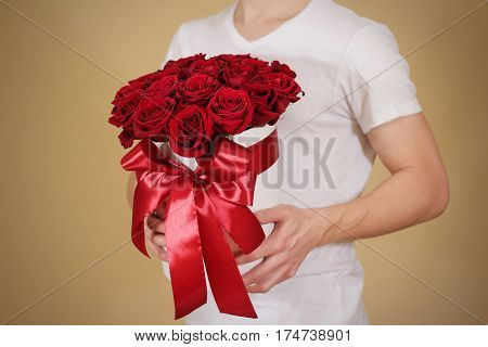 Man In White T Shirt Holding In Hand Rich Gift Bouquet Of 21 Red Roses. Composition Of Flowers In A