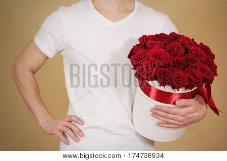 Man In White T Shirt Holding In Hand Rich Gift Bouquet Of 21 Red Roses. Composition Of Flowers In A