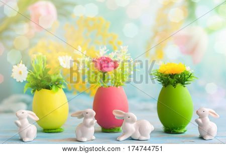 Easter decoration with spring flowers in colorful dyed eggs and white easter rabbits