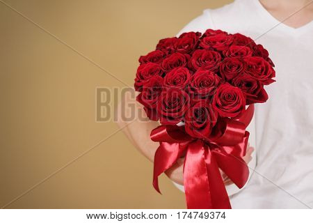 Man In White T Shirt Holding In Hand Rich Gift Bouquet Of 21 Red Roses. Composition Of Flowers In A