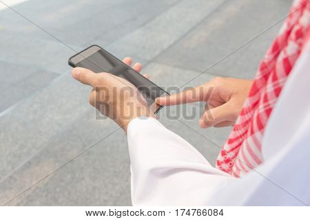Close up of young Arab Middle Eastern Businessman using mobile smartphone blurry background.