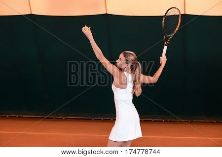 Sportswoman at the tennis court with racquet. Indoor tennis court