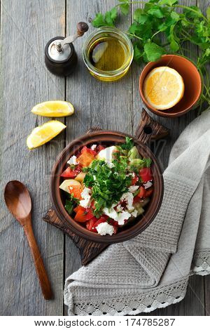 Fresh Salad Shopska of baked peppers tomato onion cucumber parsley dill and feta cheese in a ceramic bowl. Traditional Serbian food. Selective focus.Top view.
