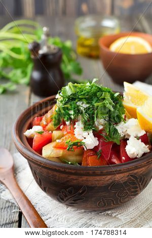 Fresh Salad Shopska of baked peppers tomato onion cucumber parsley dill and feta cheese in a ceramic bowl. Traditional Serbian food. Selective focus.