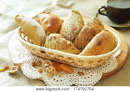 Russian pirozhki, baked patties or pies on basket with nuts and dried apricots