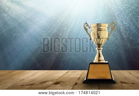champion golden trophy on wood table with copy space and blue Twinkly Lights and glitter stars light background copy space ready for your design.