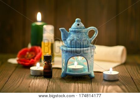 The small blue oil warmer with the candle inside placed on a wooden surface.