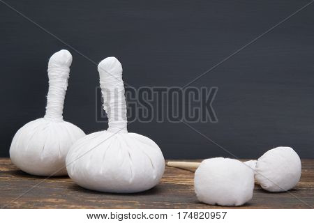 Herbal bags massage lying on a wooden board on a dark wall