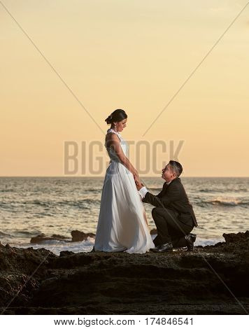 Groom Stand On Knee And Hold Bride Hand