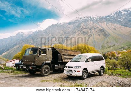 Stepantsminda, Georgia - May 22, 2016: Old Soviet Russian medium-duty truck Kamaz 53212 and SUV Mitsubishi Delica Space Gear parking together in village on summer mountains landscape in Georgia.