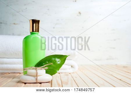 bath items. soap, towel, liquid an fresh leaf with copy space on wooden background