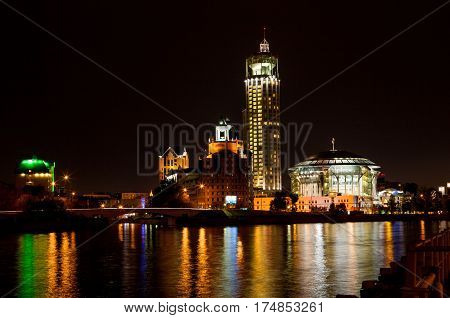 Night panorama of the Moscow House of Music is reflected in the Moscow river, Russia.