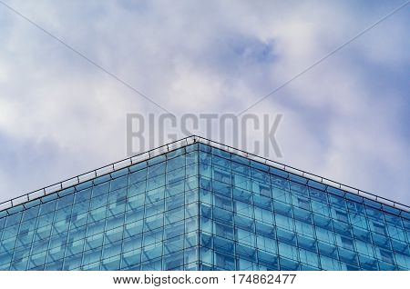 Modern glossy facade of building against of the cloudy sky. Multilayer facade system of a high-rise building. Spider facade fixing system. Symmetry composition