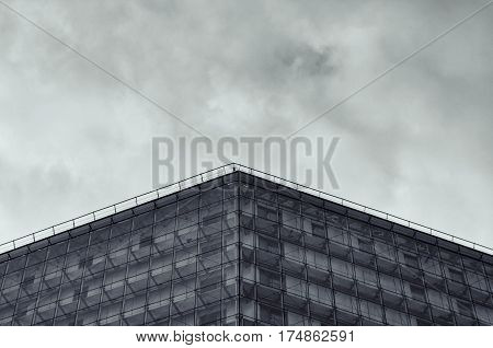 Modern glossy facade of building against of the cloudy sky. Multilayer facade system of a high-rise building. Spider facade fixing system. Symmetry composition