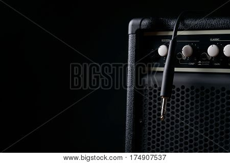 Close up of Black guitar amplifier with jack cable on black background.
