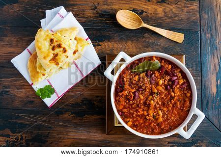 Traditional Polish cuisine stewed Breton beans with minced beef bacon mashed tomatoes onion garlic paprika bay leaves and spices. White casserole on wooden rustic table top view.