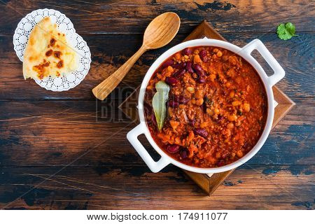 Traditional Polish cuisine stewed Breton beans with minced beef bacon mashed tomatoes onion garlic paprika bay leaves and spices. White casserole on wooden rustic table top view.