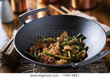 large cast iron wok with chicken and string bean stir fry