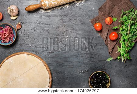 Frame of pizza dough with set ingredients for cooking vegetarian pizza on the dark stone surface top view. Healthy food