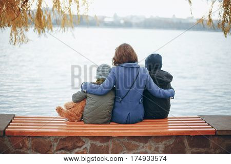 mother of two boys sitting on a bench near the river