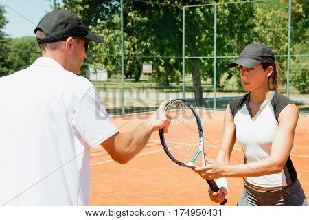 Learning tennis - female student with instructor on court