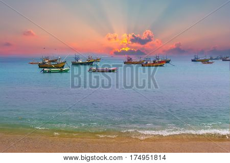 Beautiful sunrise tropical beach white sand turquoise ocean water . Boats of fishermen on the water.
