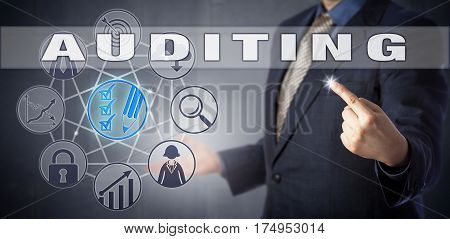 Male corporate accountant in blue business suit activating AUDITING. Business process metaphor and information technology concept for independent examination of accounts assurance and compliance.
