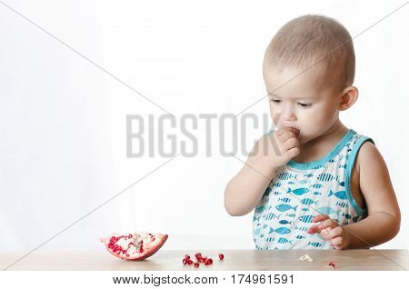 Baby eats a pomegranate ripe and juicy very tasty and joyfully