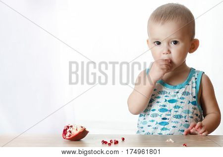 Baby eats a pomegranate ripe and juicy very tasty and joyfully