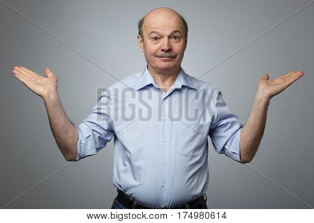 A Man In An Informal Shirt Raises His Arms To The Sides In Bewilderment And Confusion