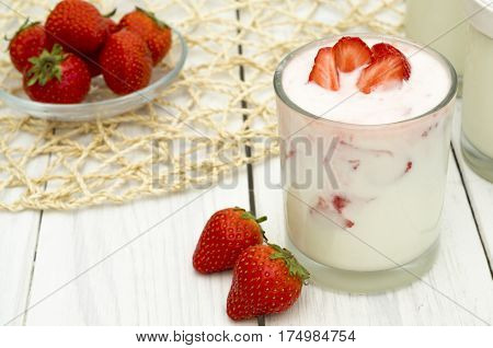 Strawberry yogurt on the white wooden background. Healthy diet