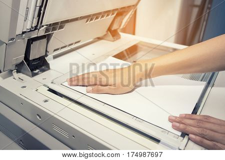 woman hands putting a sheet of paper into a copying device