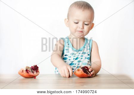Baby eats a pomegranate ripe and juicy very tasty and joyfully