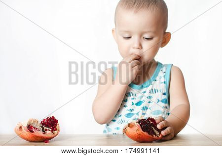 Baby eats a pomegranate ripe and juicy very tasty and joyfully