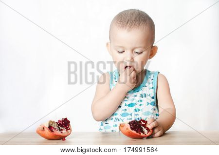 Baby eats a pomegranate ripe and juicy very tasty and joyfully
