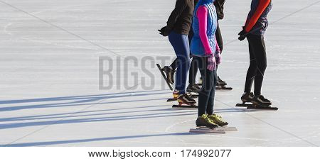 Speed skating sportsmen on competition- ice rink at winter sunny day - children's sport concept, telephoto