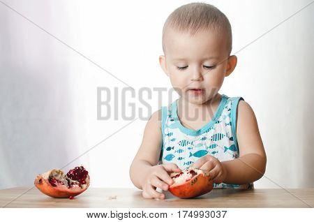 Baby eats a pomegranate ripe and juicy very tasty and joyfully