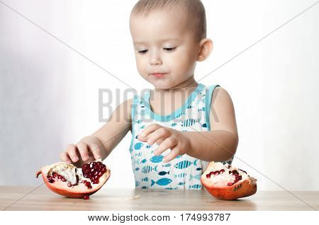 Baby eats a pomegranate ripe and juicy very tasty and joyfully