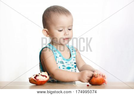 Baby eats a pomegranate ripe and juicy very tasty and joyfully