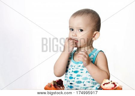 Baby eats a pomegranate ripe and juicy very tasty and joyfully